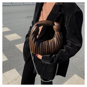 Détail du sac plissé en cuir marron foncé avec poignée nouée et chaîne argentée