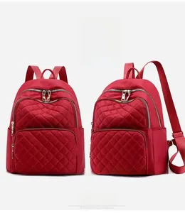 Detail view of wine red quilted nylon backpack with front zippered pocket and sturdy straps