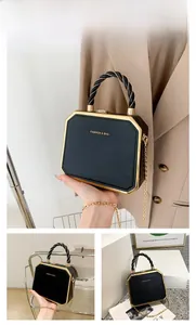 Detailed close-up of a black octagonal chain box bag with gold metal edges and handle