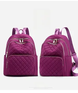 Detail of purple quilted nylon backpack showing diamond stitching and zipper compartments