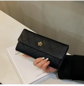 Close-up of black quilted leather wallet featuring a golden camellia flower buckle detail