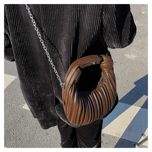 Détail d'un sac à main plissé marron en cuir avec chaîne argentée lors d'une séance photo de rue