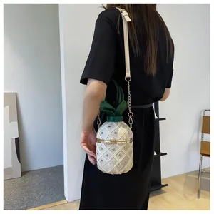 Détail du sac seau en forme d'ananas avec clous dorés et décor de feuilles vertes