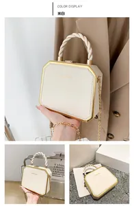 Detail of cream hexagonal box bag featuring gold trim and woven handle accessories