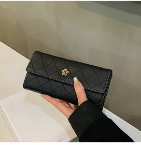 Close-up of black quilted long wallet featuring a gold camellia flower clasp detail
