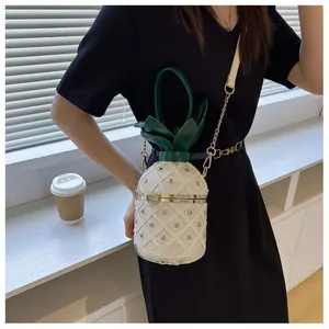 Détail du sac seau ananas avec texture matelassée blanche, clous dorés et poignée feuille