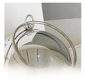 Detailed close-up of the elegant round metal handle on a silver spherical acrylic clutch bag