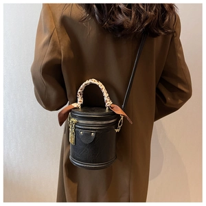 Détail d'un sac seau en cuir noir avec foulard en soie et fermetures éclair dorées