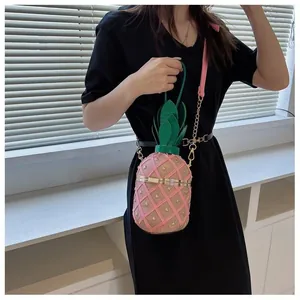 Détail du sac seau en forme d'ananas rose avec clous dorés et feuilles vertes