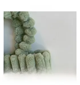 Détail d'un sac cabas vert clair en peluche avec rayures en fausse fourrure et anse à pompons