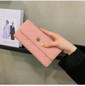 Detail of pink quilted wallet featuring a golden camellia flower clasp held by hand