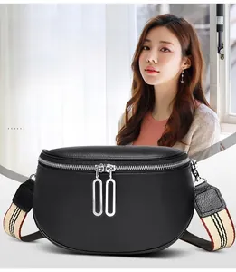 Détail du sac banane en cuir noir avec double zip argenté et large bandoulière rayée