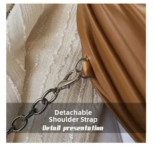 Détail d'un sac à main marron plissé avec une bandoulière en chaîne argentée amovible