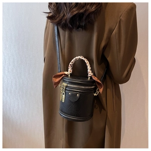 Sac seau noir avec foulard en soie et cadenas doré porté à l'épaule pour un style rétro
