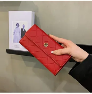 Detail of red quilted leather long wallet featuring a gold camellia flower logo accent