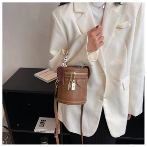 Détail d'un sac seau en cuir marron avec foulard léopard et finitions dorées