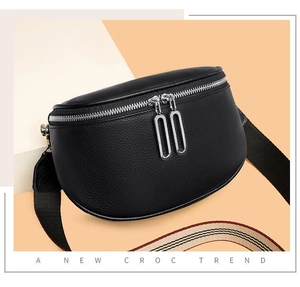 Détail du sac ceinture en cuir noir embossé croco avec une bandoulière rayée amovible