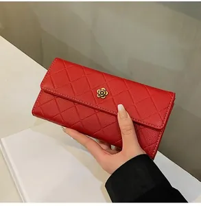 Macro shot of red quilted faux leather wallet featuring a golden camellia floral clasp