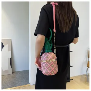 Sac seau ananas rose à clous dorés et feuilles vertes porté par un mannequin de mode