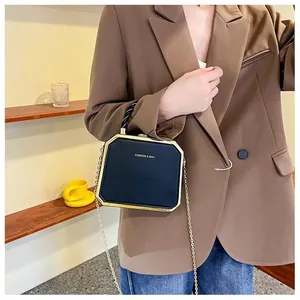 Octagonal black matte handbag with gold metal frame and woven handle shown on model