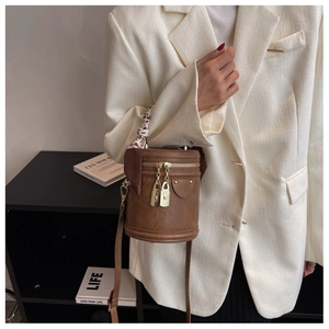 Détail d'un sac seau en cuir marron avec serrure dorée et foulard en soie au manche