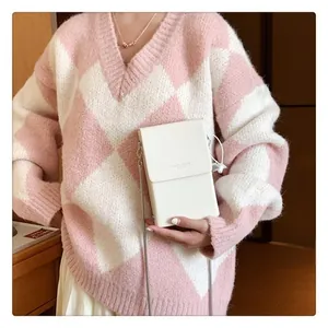Chic cream mini crossbody bag with metal chain strap worn over a checkered sweater
