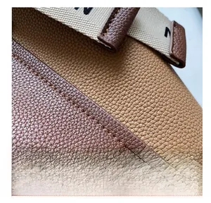 Detail of lychee pattern leather stitching with precise seams and woven strap on bucket bag
