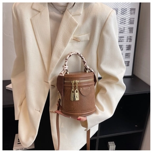 Détail d'un sac seau en cuir marron avec cadenas dorés et poignée en foulard de soie