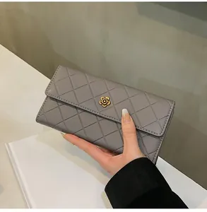 Detail of grey quilted long wallet featuring gold camellia buckle and texture