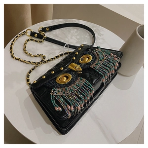 Macro view of owl-shaped quilted leather bag with colorful beaded fringe and gold hardware