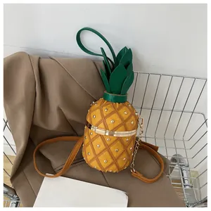 Détail du sac seau en forme d'ananas avec rivets dorés et bordure de feuilles