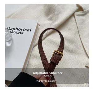 Detail of adjustable brown pebble leather shoulder strap with gold buckle on bucket bag
