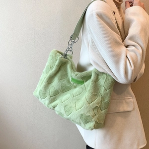 Chic green plush tote bag with heart pattern and silver chain strap on white blazer