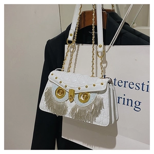 Detail of owl-shaped crossbody bag featuring silver tassels and golden metal accents