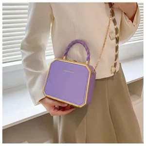 Detail of purple square box bag featuring golden trim and fashion typography on front