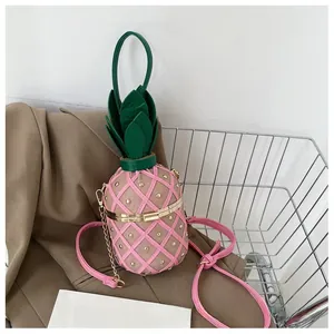 Détail du sac seau ananas rose avec rivets dorés et poignée en forme de feuilles vertes