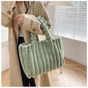Détail d'un sac cabas en peluche vert clair avec rayures douces et poignée à boules texturées