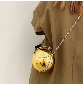 Golden spherical chain crossbody bag with metal ring handle shown on a model side view