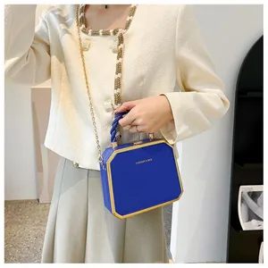 Detail of blue octagonal hard shell handbag with golden metal edges and chain strap