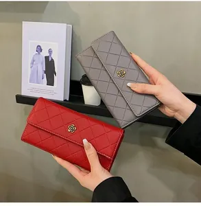 Detail of long quilted wallet featuring camellia metal buckle and flap closure