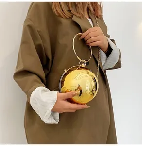Detailed view of a gold spherical acrylic evening bag with metal ring handle and chain strap