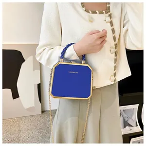 Detail of royal blue geometric handbag with gold metal trim and woven handle