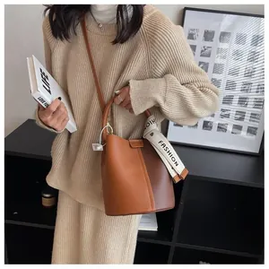 Chic two-tone bucket bag with litchi grain texture and branded fabric shoulder strap