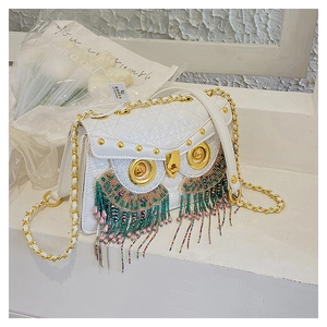 Detail of owl shaped crossbody bag featuring colorful beaded tassels and gold metal accents
