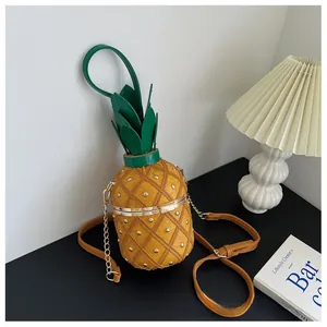 Détail du sac seau ananas avec rivets dorés, couvercle feuille verte et bandoulière chaîne