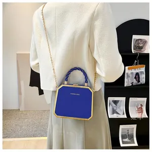 Deep blue octagonal bag with gold frame and woven handle shown from a back perspective