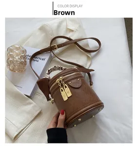 Détail d'un sac seau en cuir marron avec poignée en foulard léopard et détails dorés