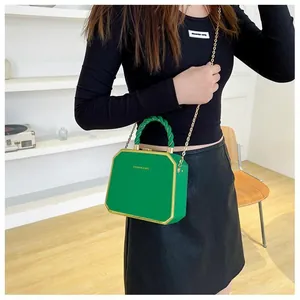 Detail of green octagonal hard shell bag with gold chain strap and fashion lettering