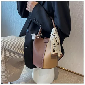Detail view of contrast color bucket bag with silk scarf accessory and top handle