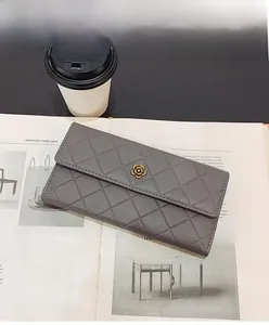 Macro shot of grey quilted wallet with gold camellia clasp on a fashion magazine
